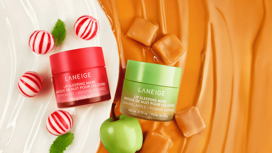 Bilden visar två burkar av LANEIGE Lip Sleeping Mask, en med smak av pepparmint och en annan med smak av karamelliserat äpple. Produkterna är snyggt placerade mot en kontrasterande bakgrund som framhäver deras färger och texturer.