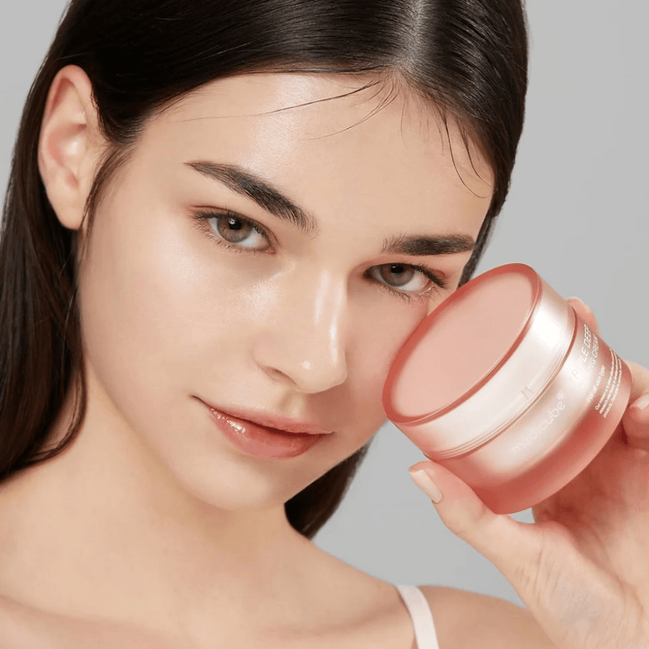 Bilden visar en kvinna som håller en burk med Triple Collagen Cream. Krämen är designad för att förbättra hudens elasticitet och återfuktning. Kvinnans hud ser slät och välvårdad ut.