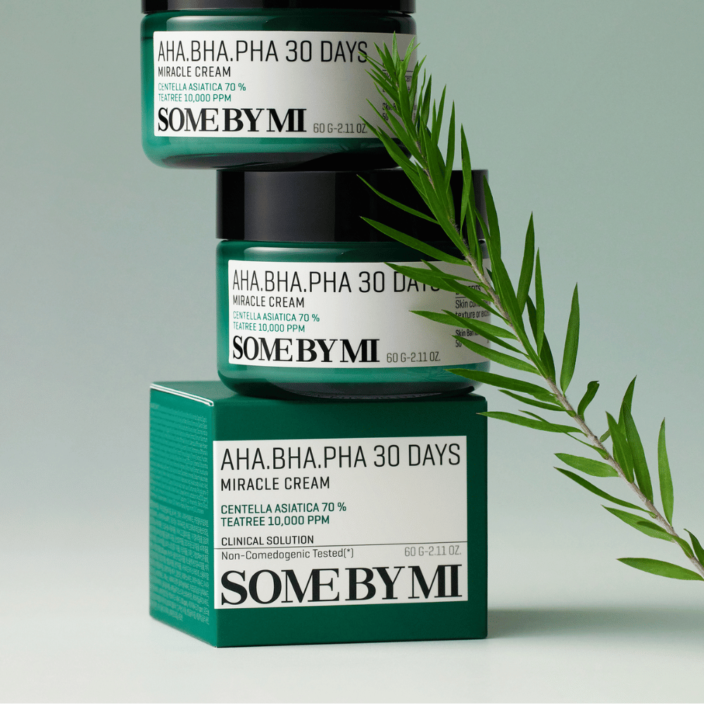 An image showing two jars of "SOME BY MI AHA, BHA, PHA 30 Days Miracle Cream" stacked on a green-toned surface. The cream, which is rich in centella asiatica and tea tree oil, is designed to improve skin quality and alleviate problem skin. It works moisturizing and soothing.
