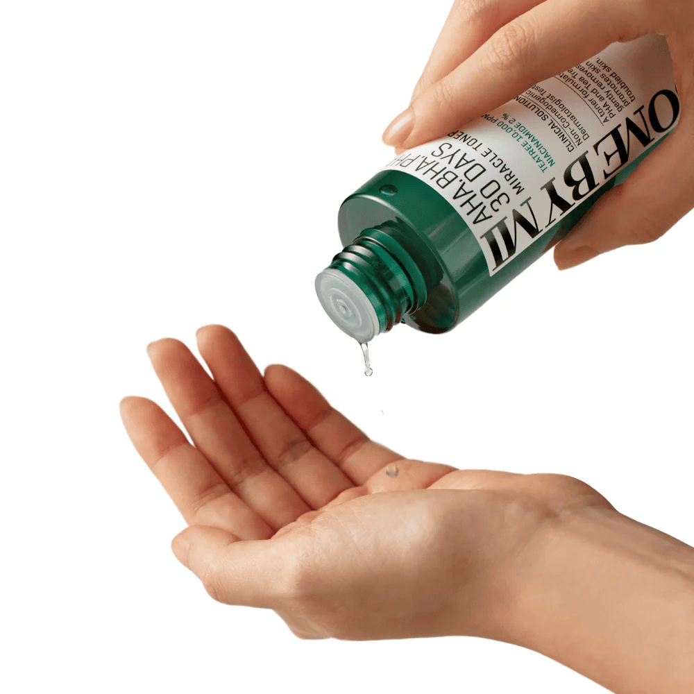 A hand holds a green bottle with the text "AHA, BHA, PHA 30 Days Miracle Toner" and squeezes out a clear liquid into the palm of the other hand, ready for use.