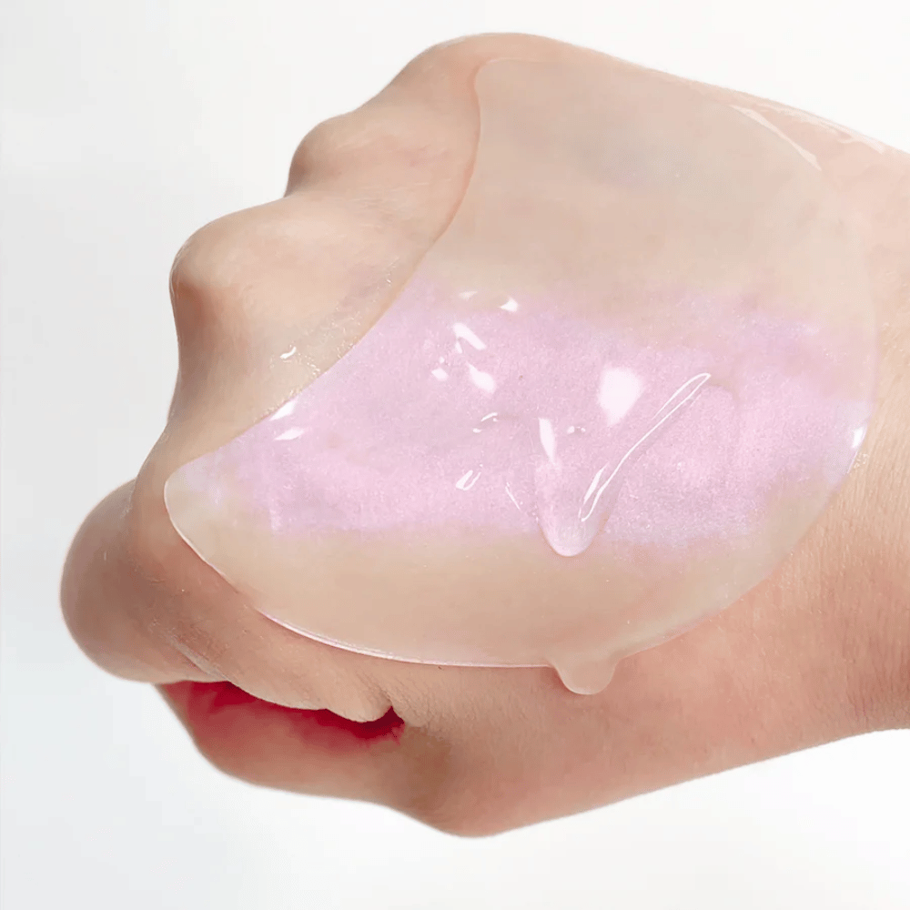 Pink hydrogel eye patch with retinol displayed on a hand, moisturizing and radiance-enhancing formula.