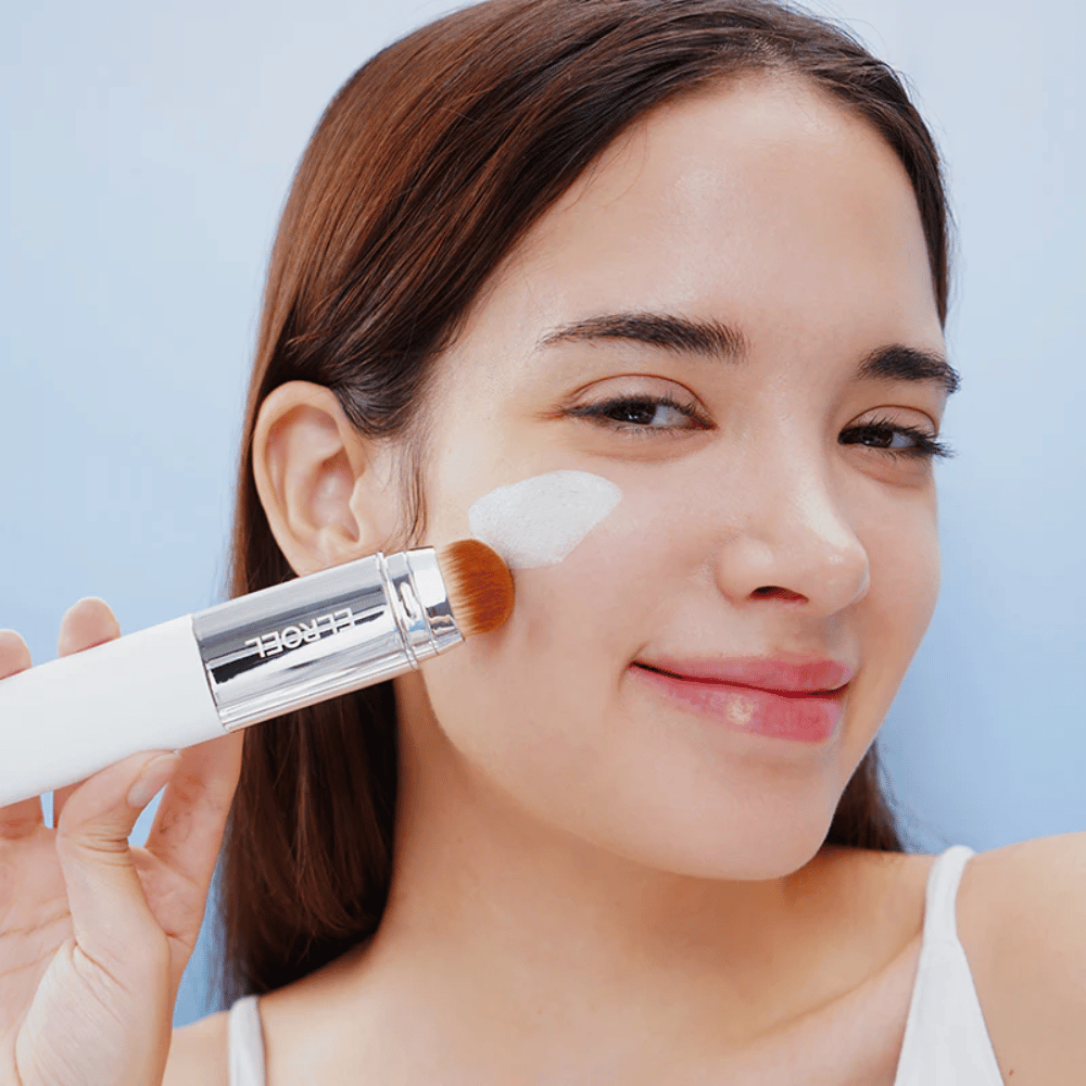 Model applies ELROEL Blanc Cover Cream Stick concealer on the cheek with a built-in brush for natural and even coverage.