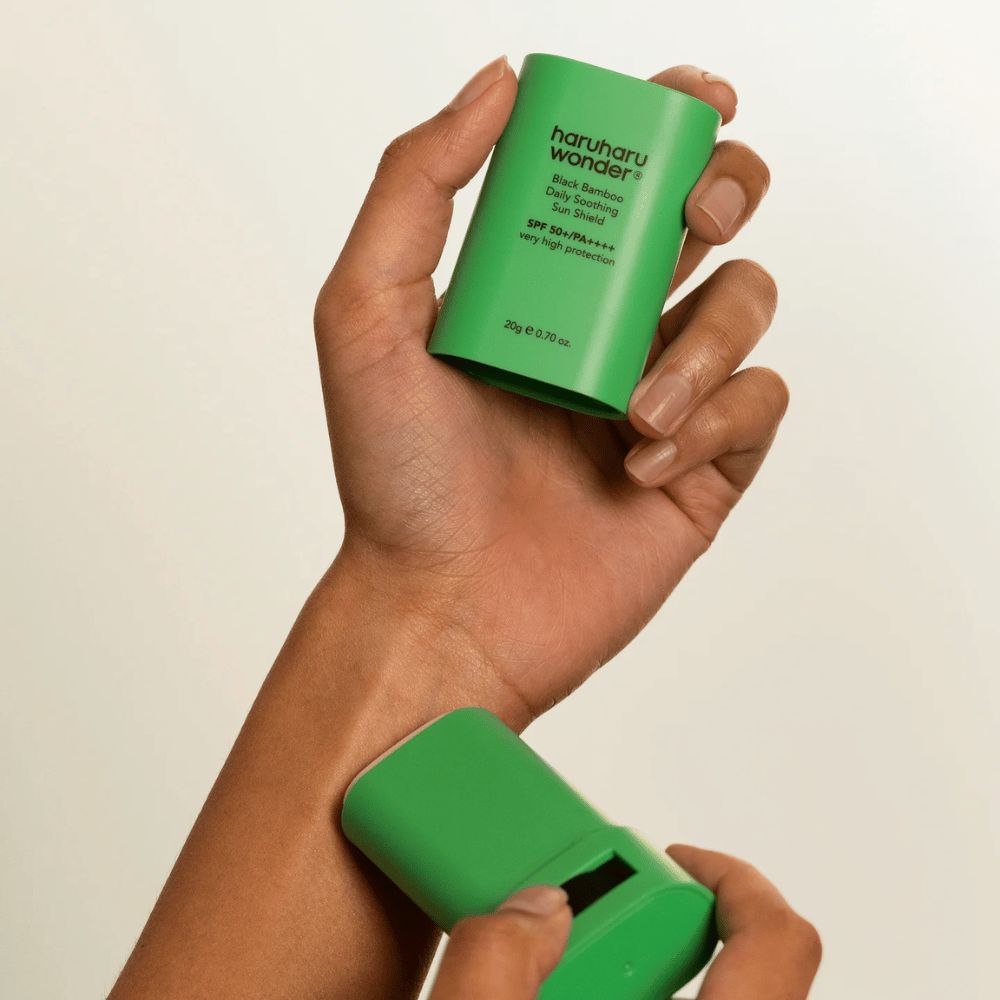 A person applies Haruharu Wonder Black Bamboo Daily Soothing Sun Shield – a green sunscreen stick with SPF 50+ PA++++ – on the wrist.