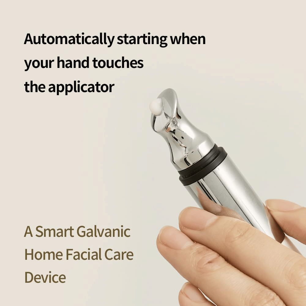 Close-up of a hand holding a galvanic applicator for eye cream with an automatic start function upon touch. Text on the image describes the function and the device as a smart home tool for facial care.