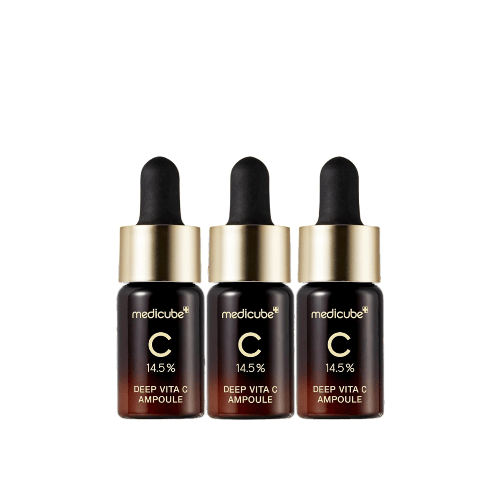 Three bottles of Medicube Deep Vita C Ampoule, with 14.5% Vitamin C, arranged in a row. The bottles have an elegant design with a dark brown base and gold-colored cap. Perfect for a brighter skin tone and smoother skin texture.