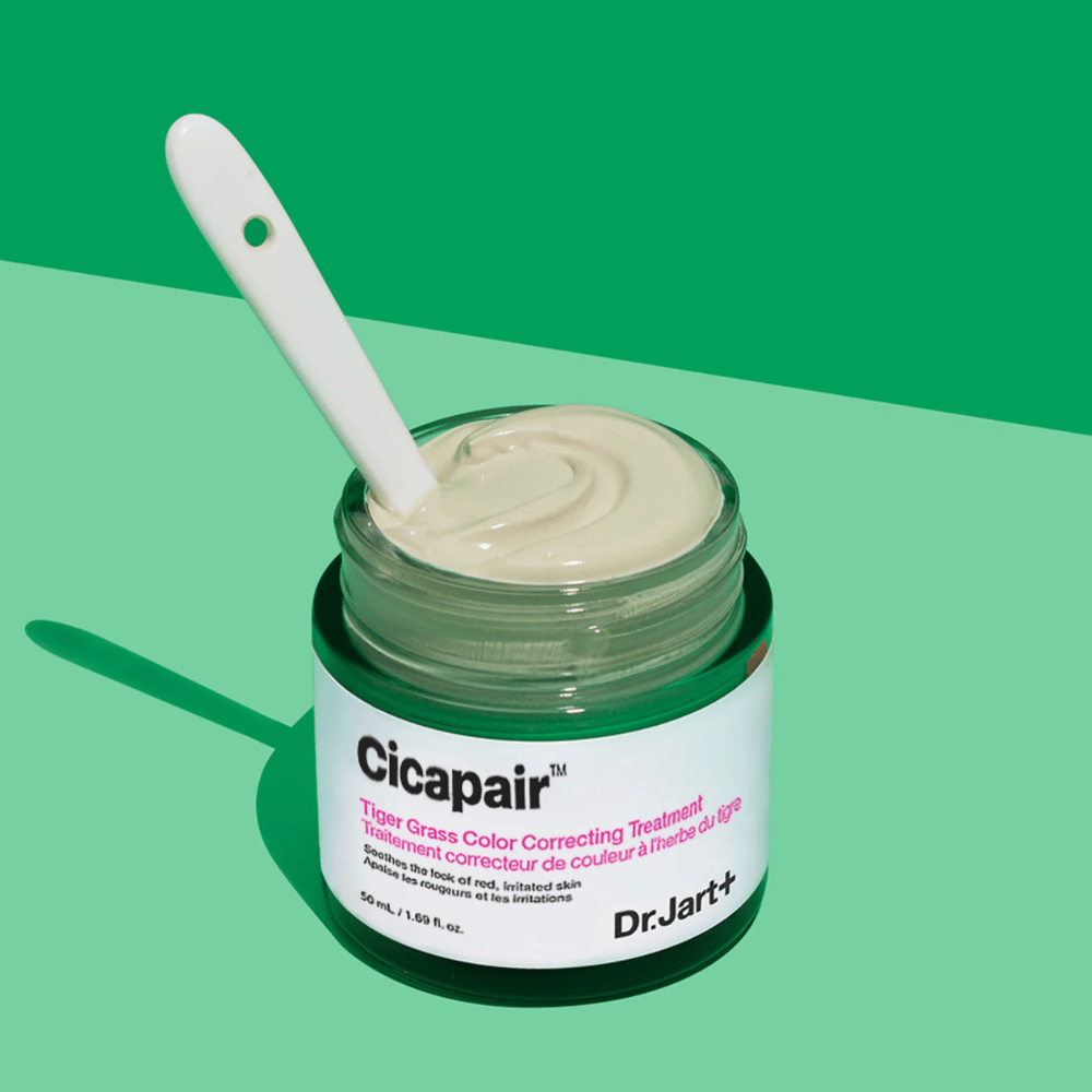 A jar of Cicapair Tiger Grass Color Correcting Treatment 50ml of Dr Jart+ on a green background.