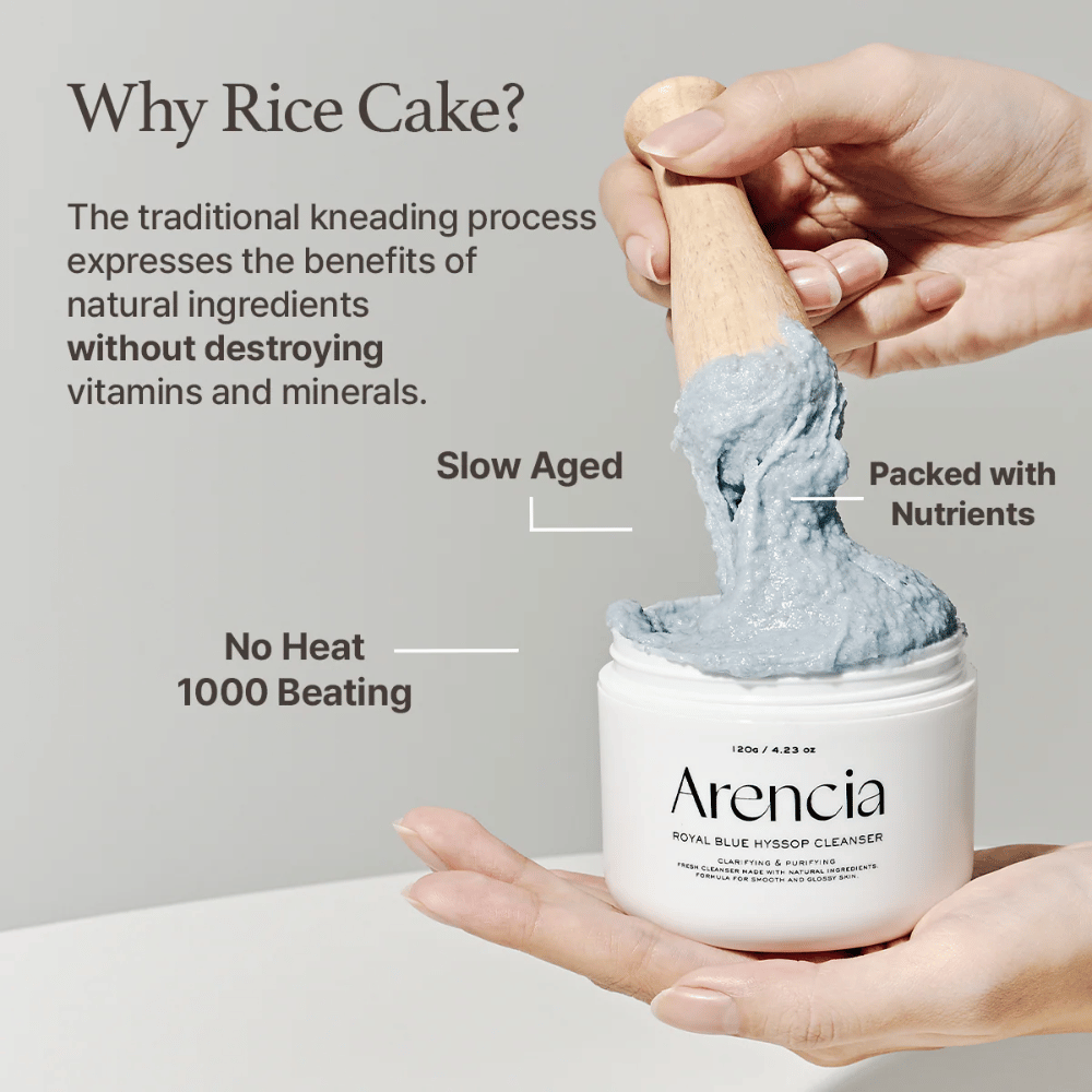 Hand holding the cleansing jar "Arencia Royal Blue Hyssop Cleanser" with a wooden spoon lifting the blue, mochi-like cleansing paste. Text in the image describes benefits of the rice dough process, such as "No Heat", "1000 Beating", "Slow Aged", and "Packed with Nutrients".