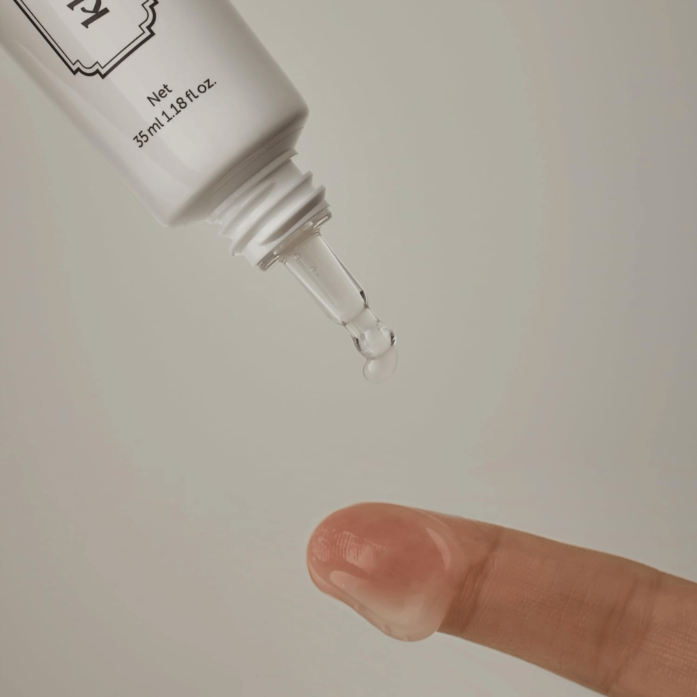 Detail image showing a clear, lightweight gel being applied from the narrow tip onto a finger. The image illustrates the product’s transparent, gel-based consistency and the precise application around the eye area.