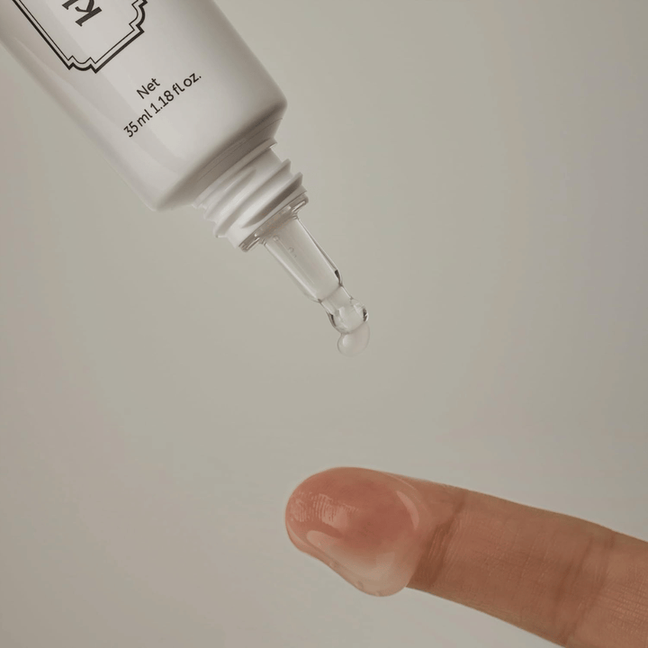 Detail image showing a clear, lightweight gel being applied from the narrow tip onto a finger. The image illustrates the product’s transparent, gel-based consistency and the precise application around the eye area.