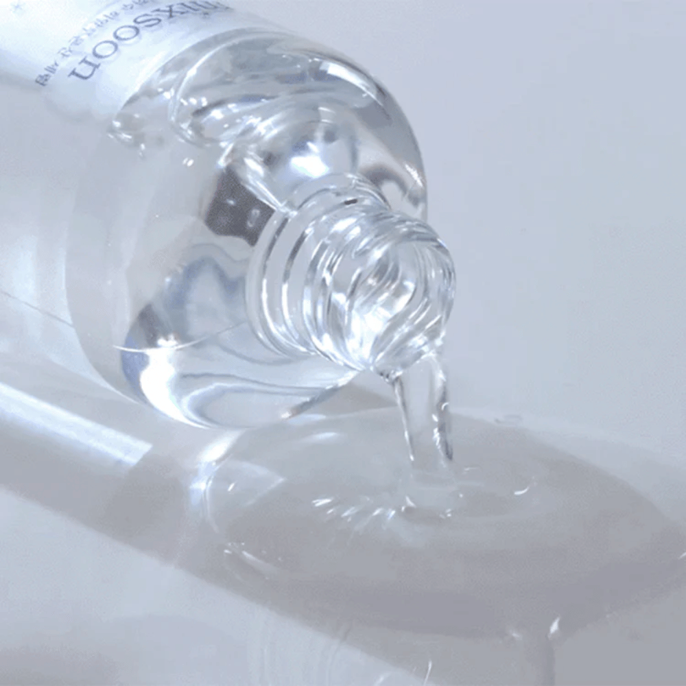 Close-up of transparent serum being poured from a bottle Mixsoon Glacier Water Hyaluronic Acid Serum onto a shiny surface.