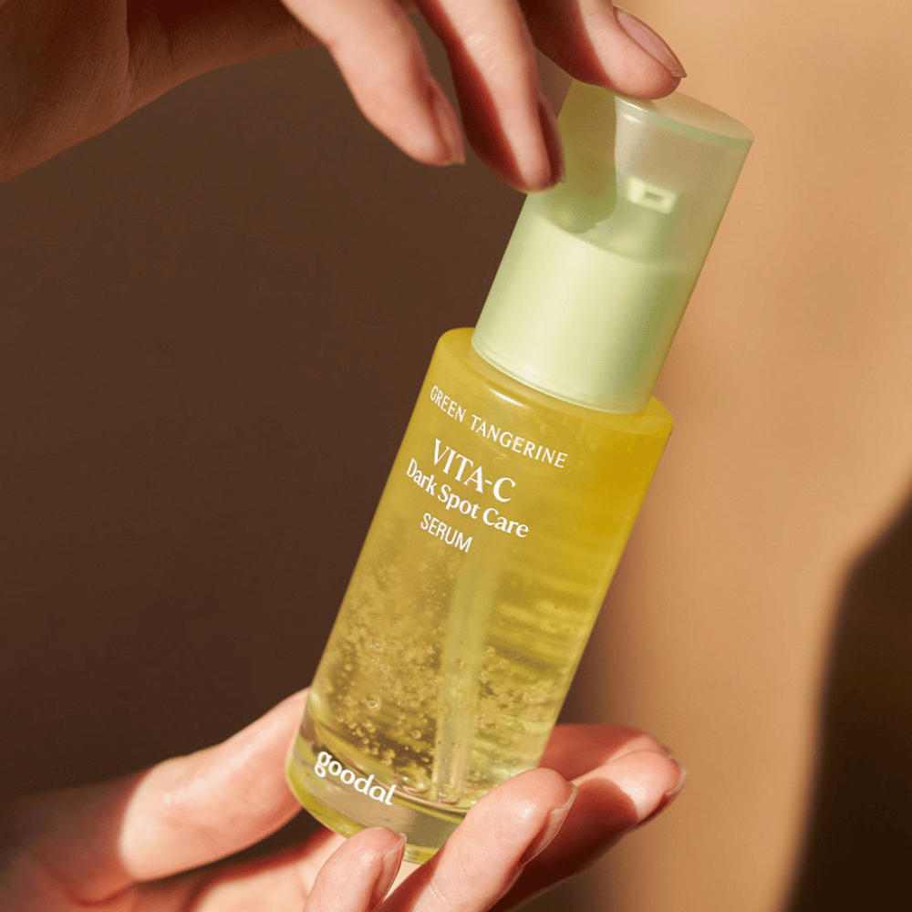 A person holding a bottle Green Tangerine Vita C Dark Spot Care Serum 40ml from Goodal for hyperpigmentation and care of dark spots.