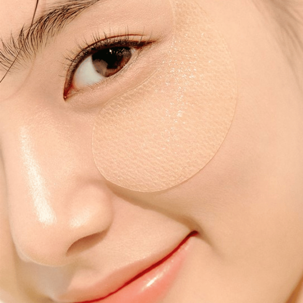 Close-up of a woman's eye with a moisturizing eye mask placed under it.