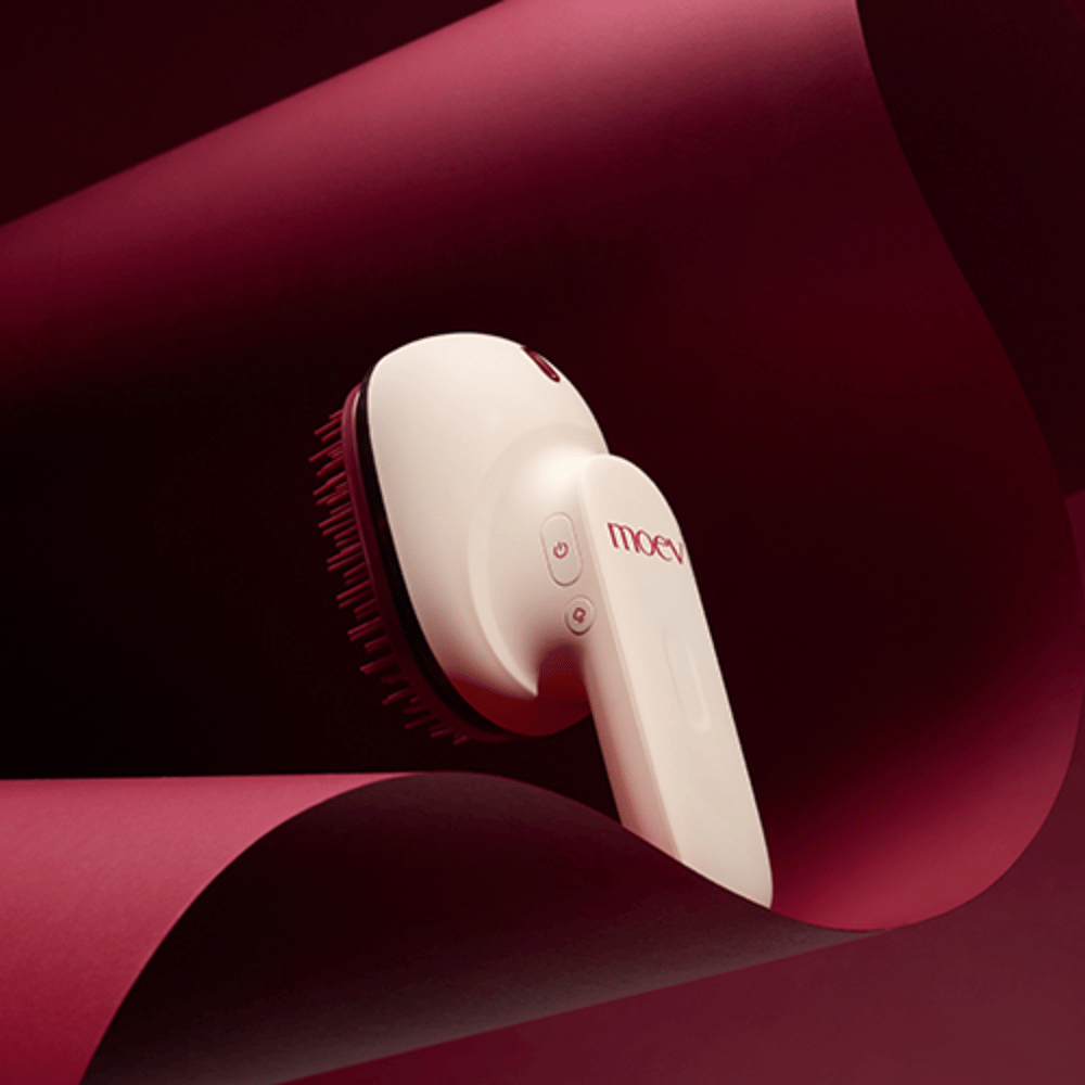 MOEV Hair Steamer Pro in elegant design against a red background. Innovative hair care brush that uses steam and heat to provide shine, softness, and strengthened hair health.