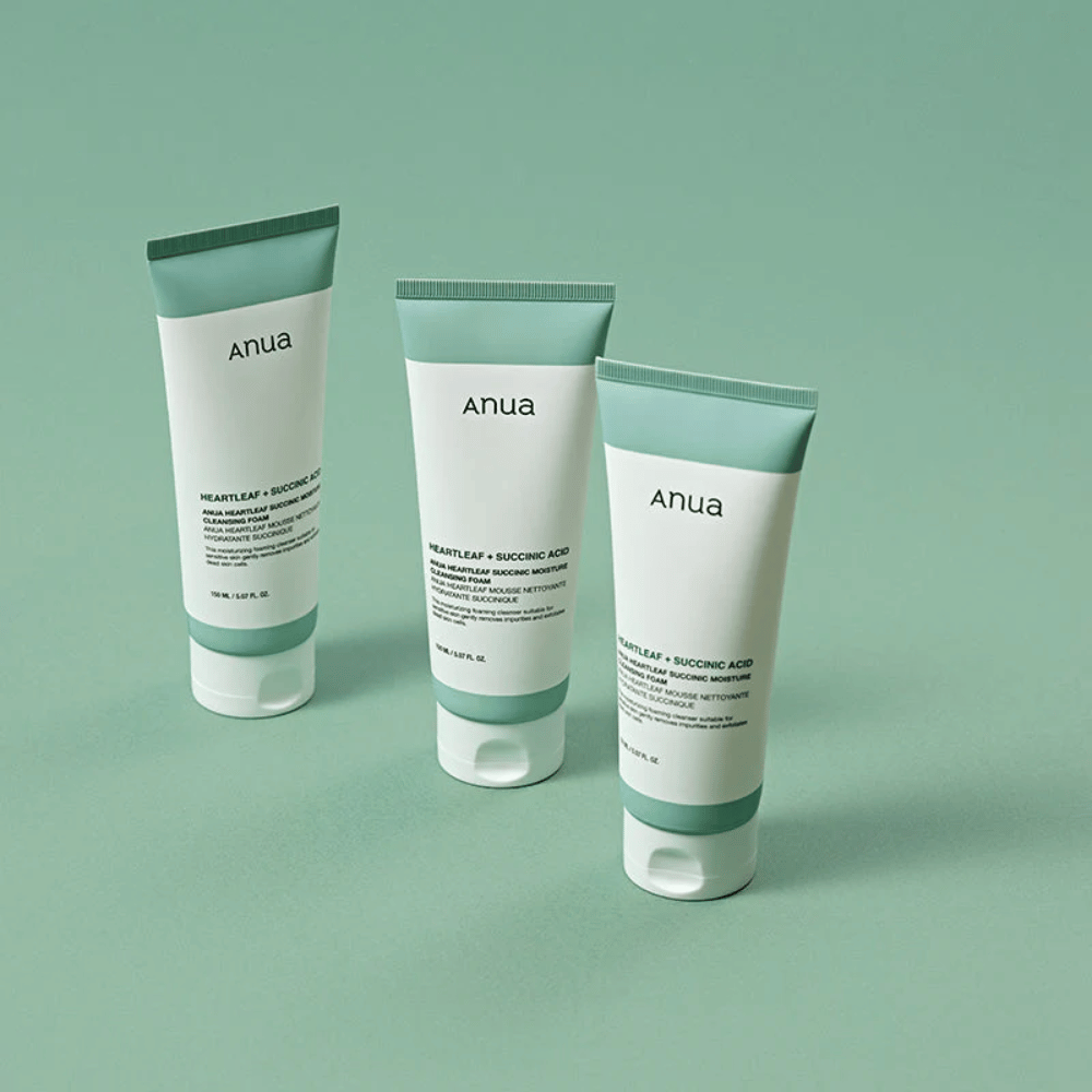 Three packages of Anua Heartleaf + Succinic Acid Moisture Cleansing Foam presented against a light green background. The image highlights the product's clean and minimalist design and gives a professional impression of the product line.
