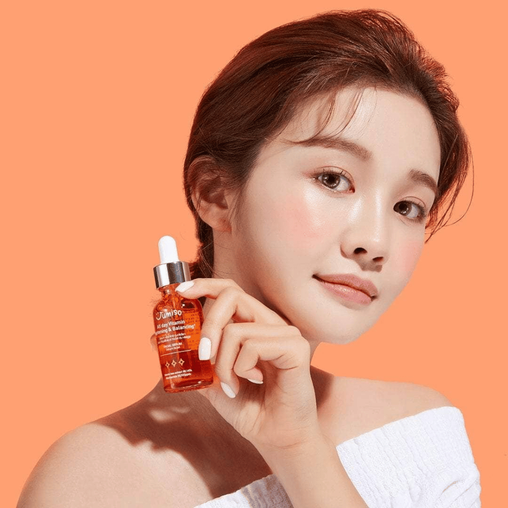 A woman holding a bottle of JUMISO All Day Vitamin Brightening & Balancing Facial Serum 30ml.