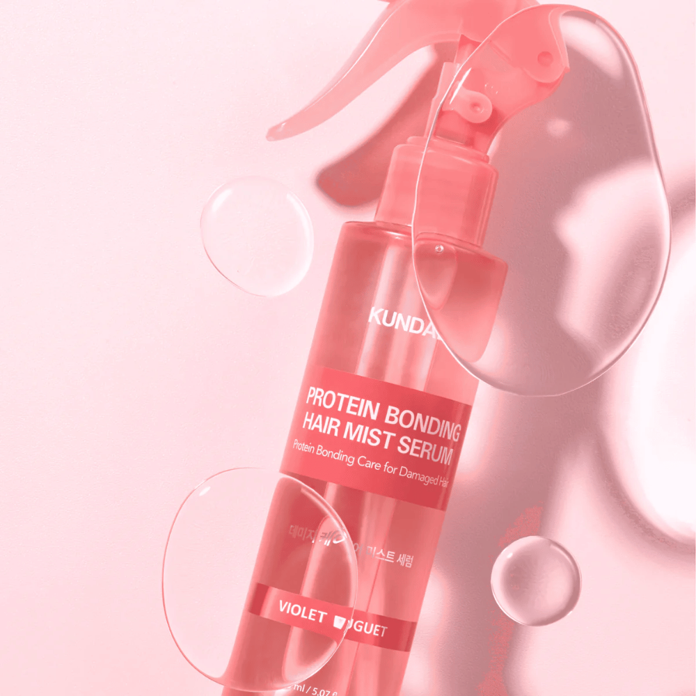 KUNDAL Protein Bonding Hair Mist Serum Violet Bouquet in pink spray bottle, photographed against pink background with water droplets.