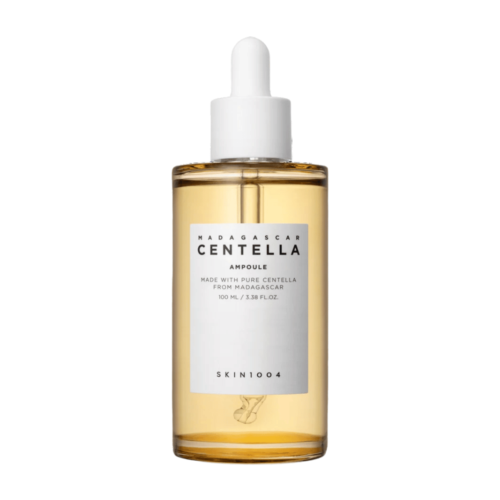 The image shows a bottle with "Madagascar Centella Asiatica 100 Ampoule" from SKIN1004. The bottle contains 100 ml and claims to be made with pure Centella from Madagascar. The product appears to be a skincare serum, and the simple label gives an impression of purity and naturalness. The bottle with a dropper cap suggests that this is a carefully dosed skincare product.