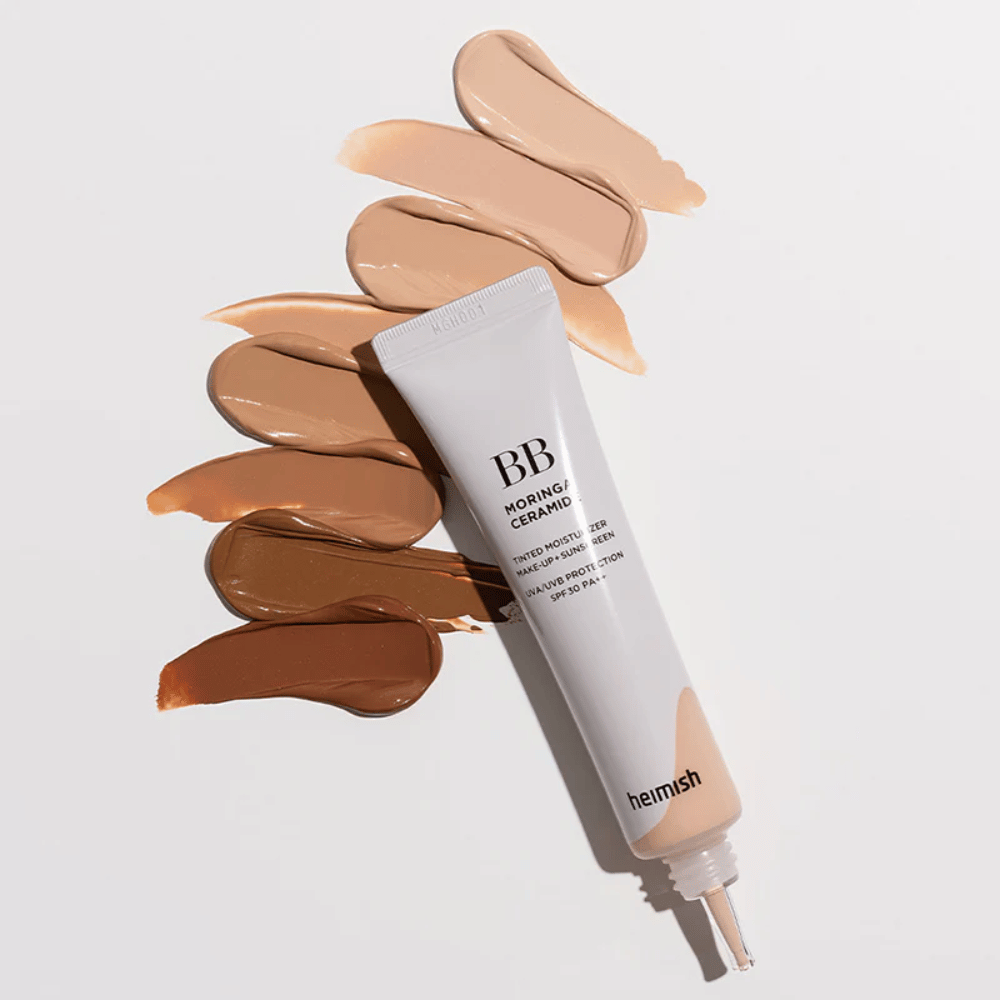 Heimish Moringa Ceramide BB Cream surrounded by several shade swatches in different skin tones. The image shows the product's wide color range and the creamy consistency that provides natural coverage and an even skin tone.