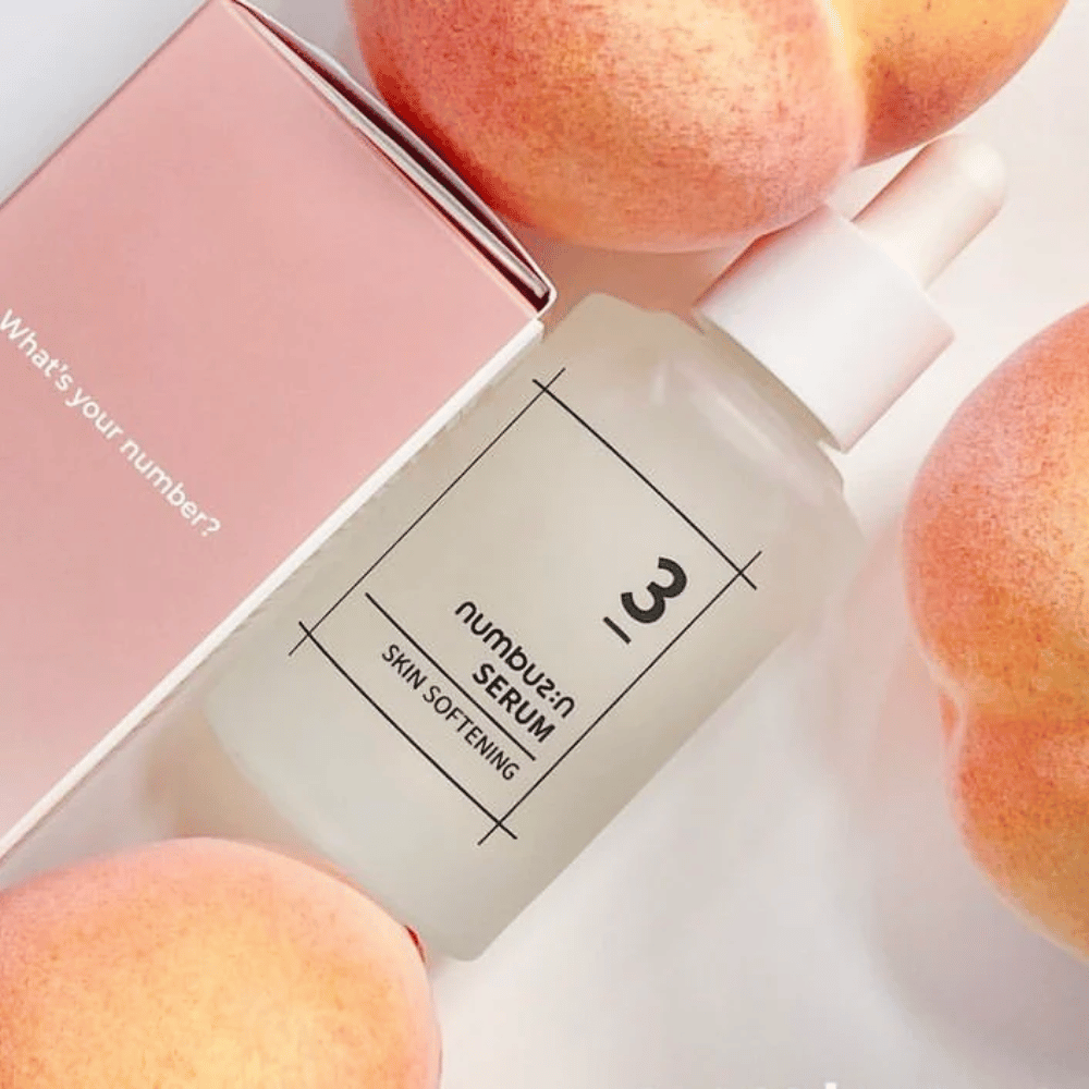 Bottle with numbus:in No.3 Skin Softening Serum surrounded by peaches and a pink box with the text "What's your number?".