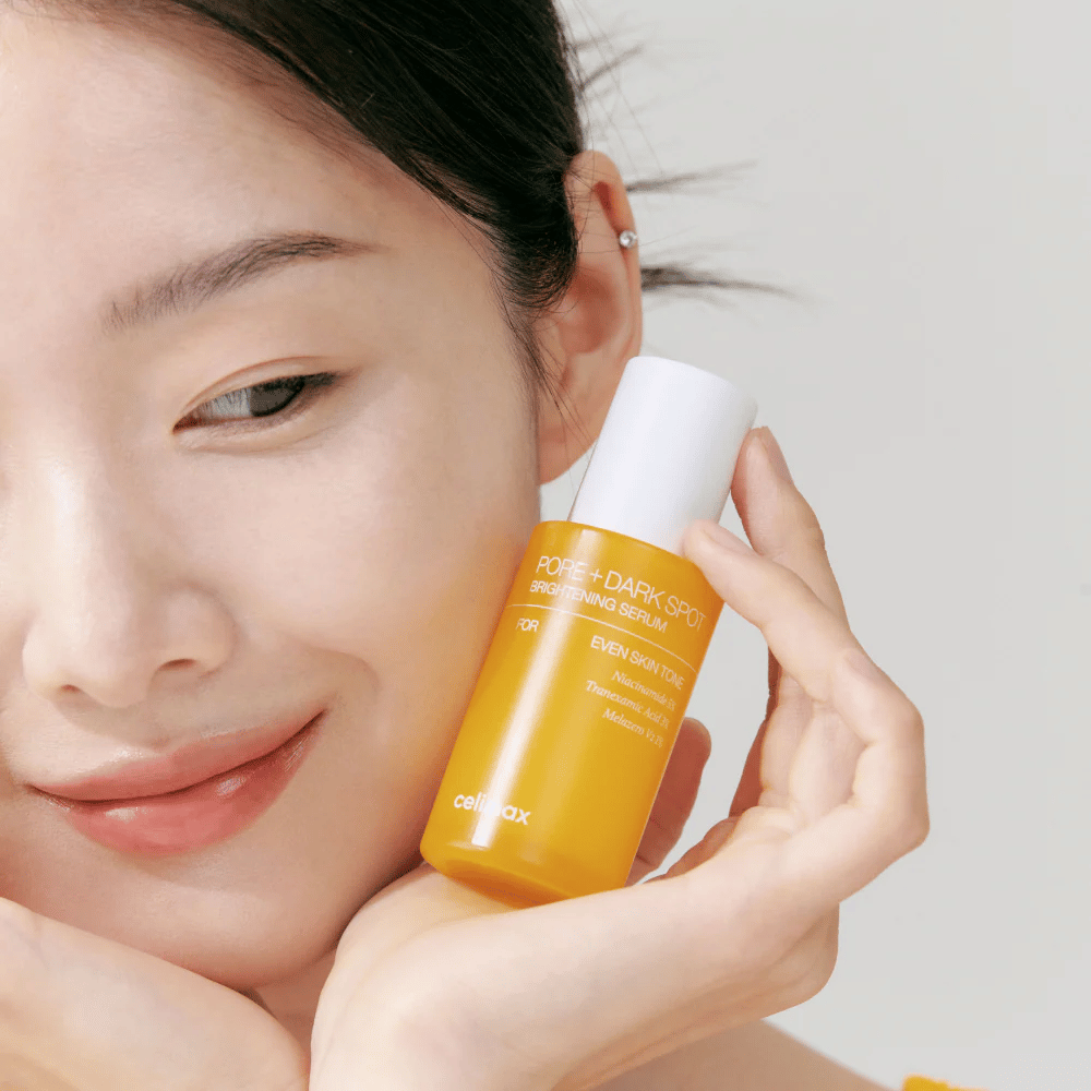 Modell håller Celimax Pore + Dark Spot Brightening Serum nära ansiktet, visar strålande hy.
