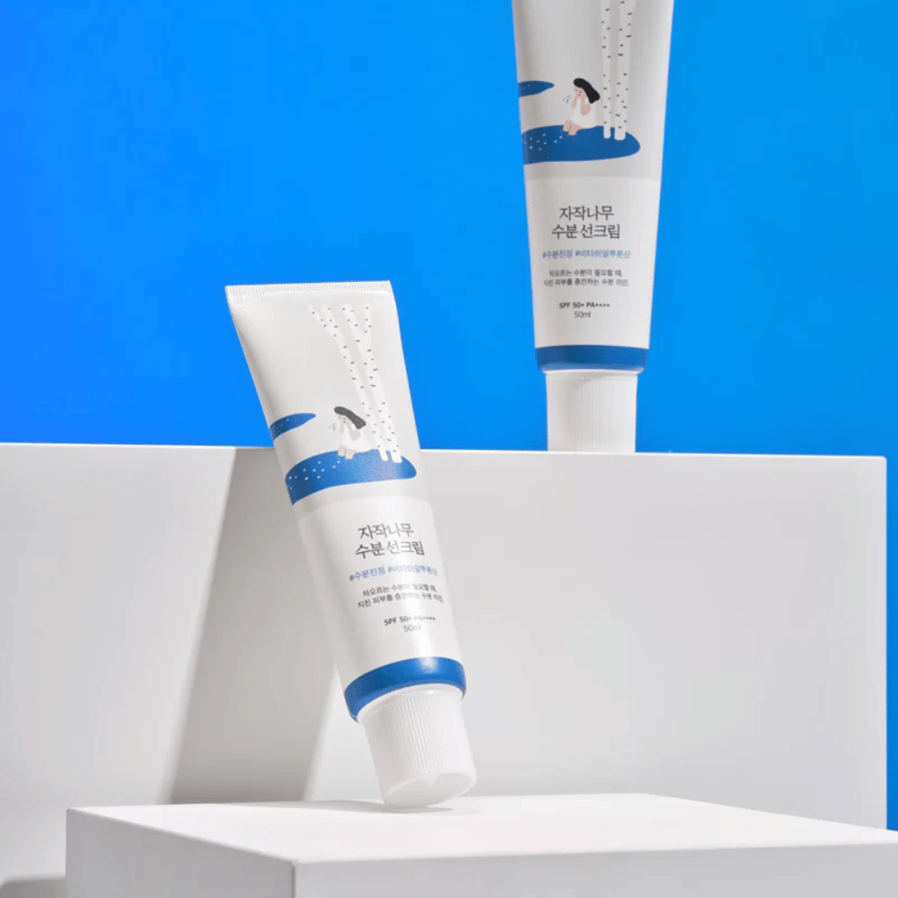 Two tubes with Round Lab Birch Juice Moisturizing Sunscreen SPF50+ PA++++ 50ml sitting on a blue background.
