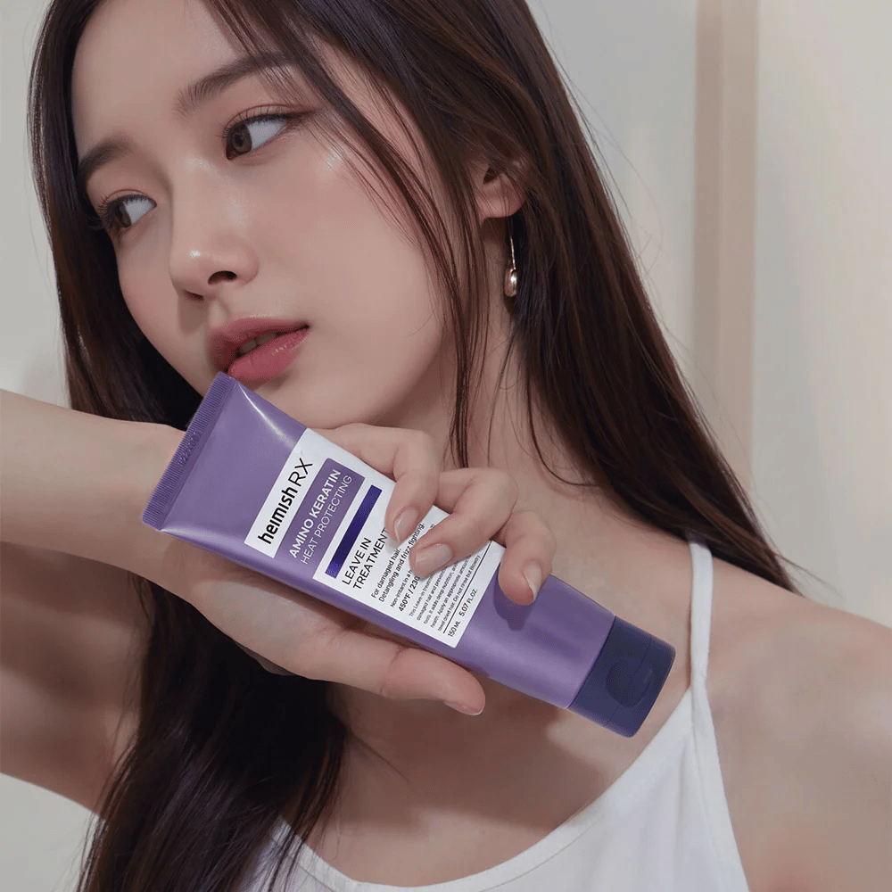 Kvinna med långt, glansigt hår håller i Heimish RX Amino Keratin Leave-In Treatment – visar produkten som ett vårdande och värmeskyddande steg i hårvårdsrutinen.