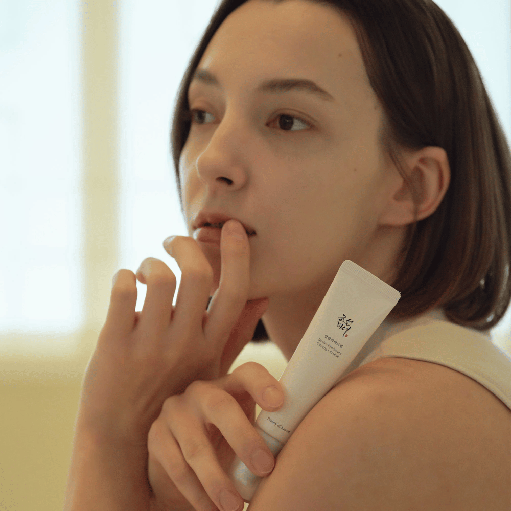 Model holds Beauty of Joseon Revive Eye Serum and carefully applies to the skin for a hydrated and smooth eye contour.