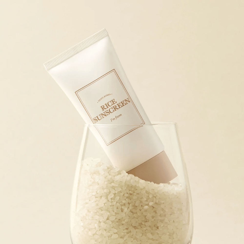 Tube with "I'm from" Rice Sunscreen, SPF50+ PA++++, placed in a glass with rice grains.