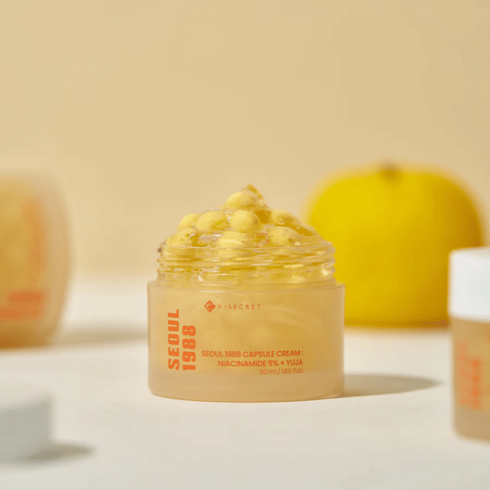 Open jar with yellow capsules next to halved yuja fruit highlighting vitamin C-rich formula.