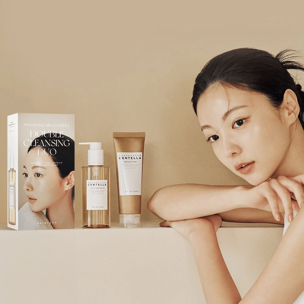 SKIN1004 Madagascar Centella Double Cleansing Duo Set med kartong, oljebaserad rengöring, skumrengöring och modell med återfuktad hud mot beige bakgrund.