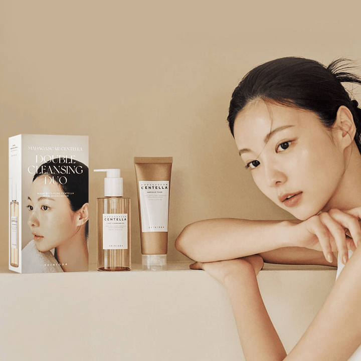 SKIN1004 Madagascar Centella Double Cleansing Duo Set med kartong, oljebaserad rengöring, skumrengöring och modell med återfuktad hud mot beige bakgrund.