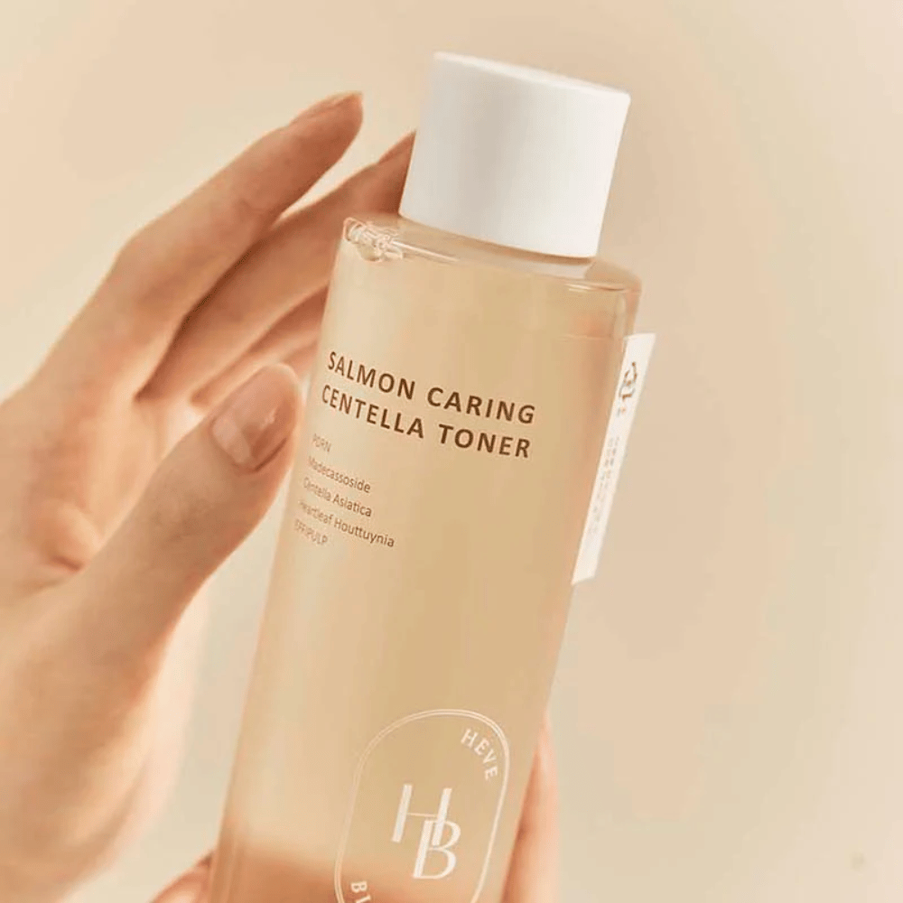 Close-up of Salmon Caring Centella Toner in hand – soothing toner with PDRN and plant extracts that help strengthen the skin and reduce the feeling of irritation.