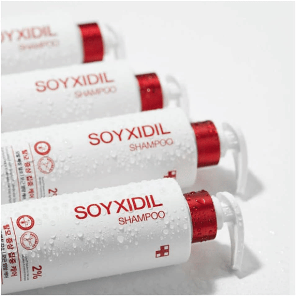 Several bottles of Medicube Soyxidil Shampoo lying in a row with water droplets – showing the product's fresh and caring feel.