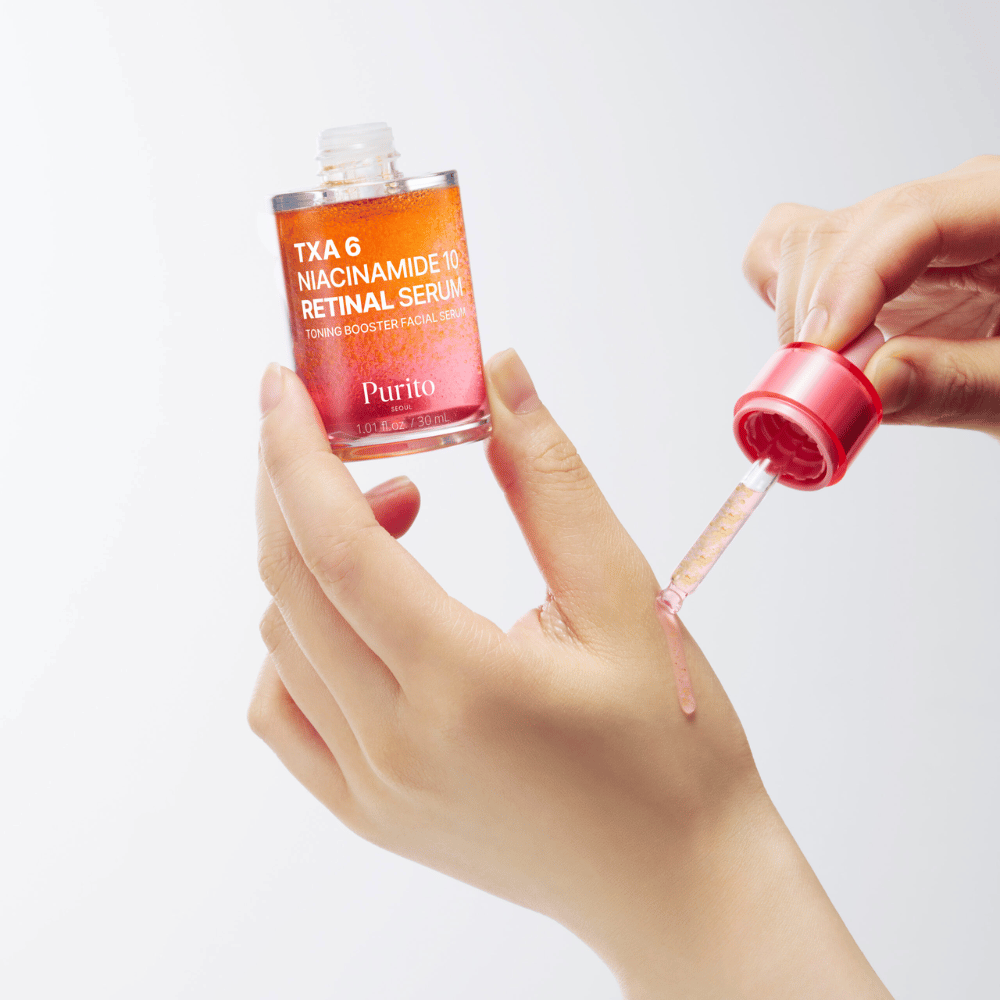 Hand applying Purito TXA 6 Niacinamide 10 Retinal Serum. Light formula with active ingredients for radiance, elasticity, and clearer skin.
