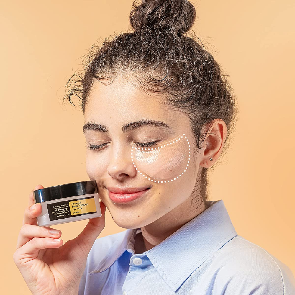 A woman holding a jar COSRX Advanced Snail Hydrogel Eye Patch 60 pcs face cream.