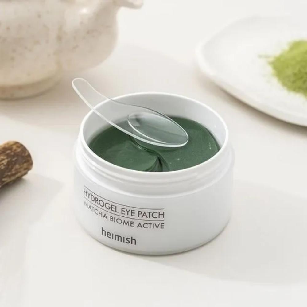 A bowl with Heimish Matcha Biome Hydrogel Eye Patch 60 plasters with a spoon.